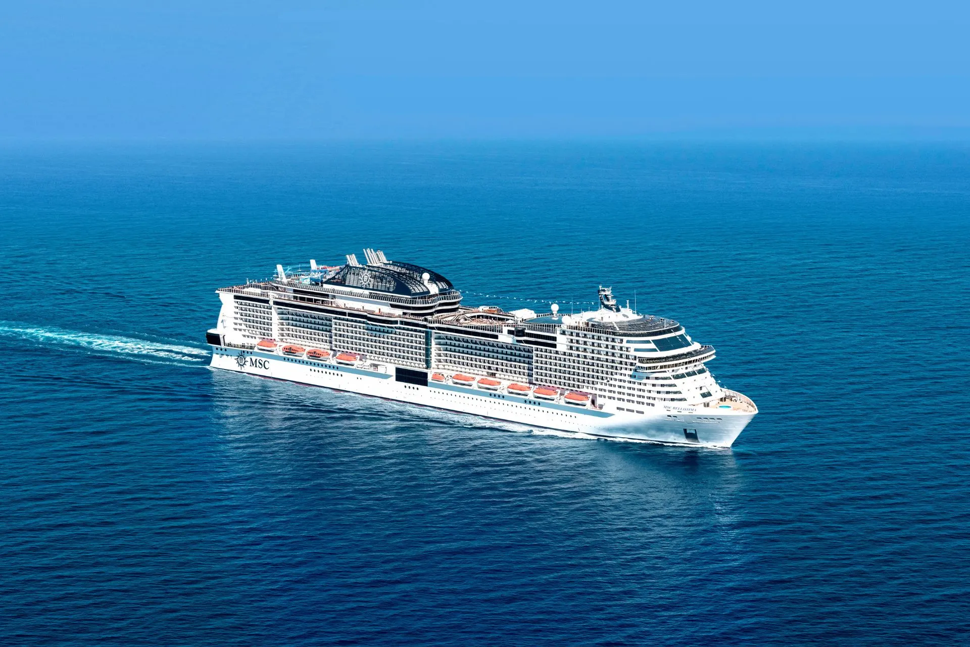 Het cruiseschip MSC Bellissima vaart over de diepe blauwe oceaan onder een heldere hemel.