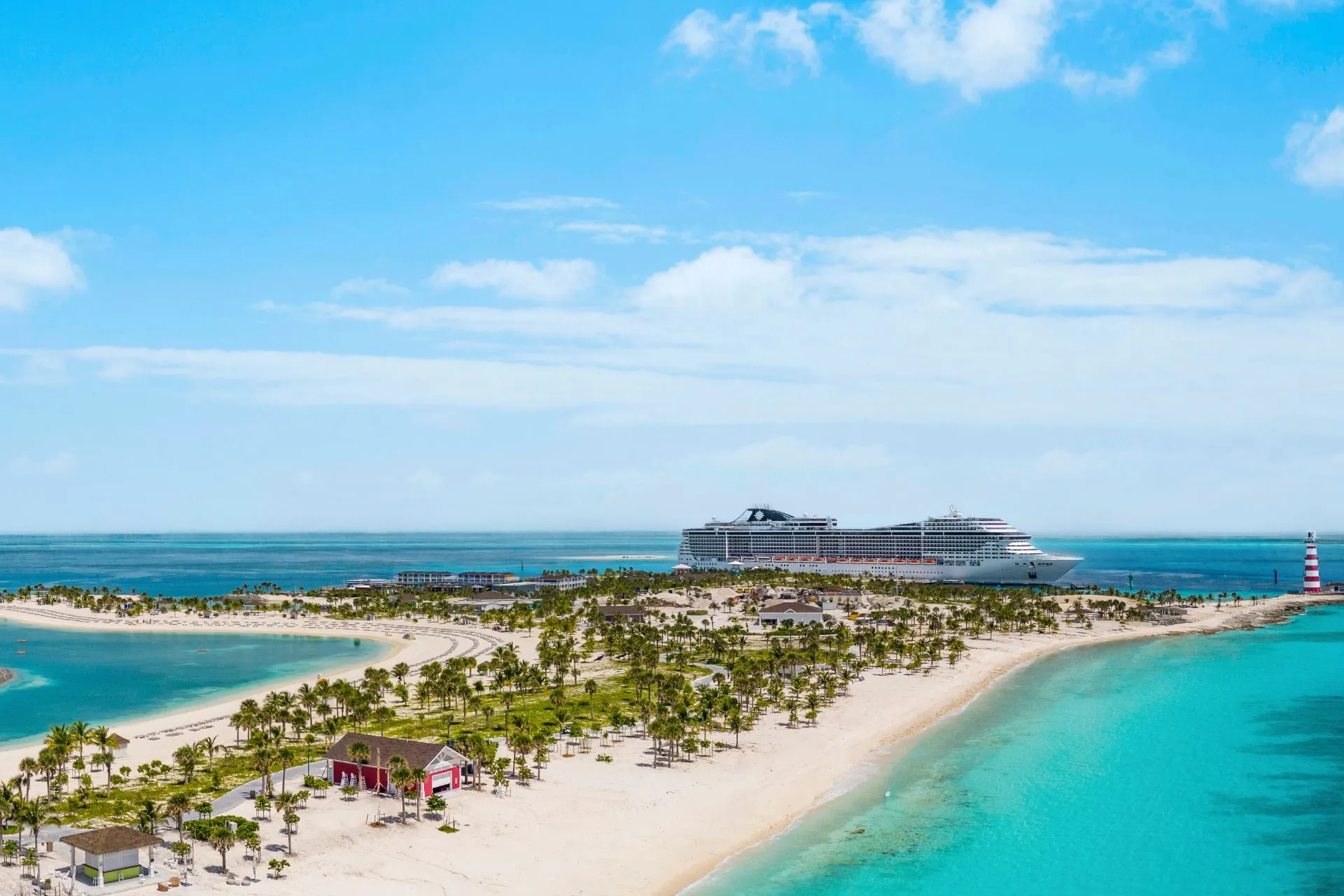  Luxe cruiseschip van MSC Cruises aangemeerd bij een tropisch privé-eiland in de Bahama’s, met witte zandstranden, palmbomen en turquoise water.