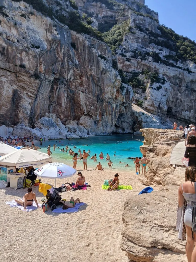 Strand met helder blauw water en mensen in Sardinië.