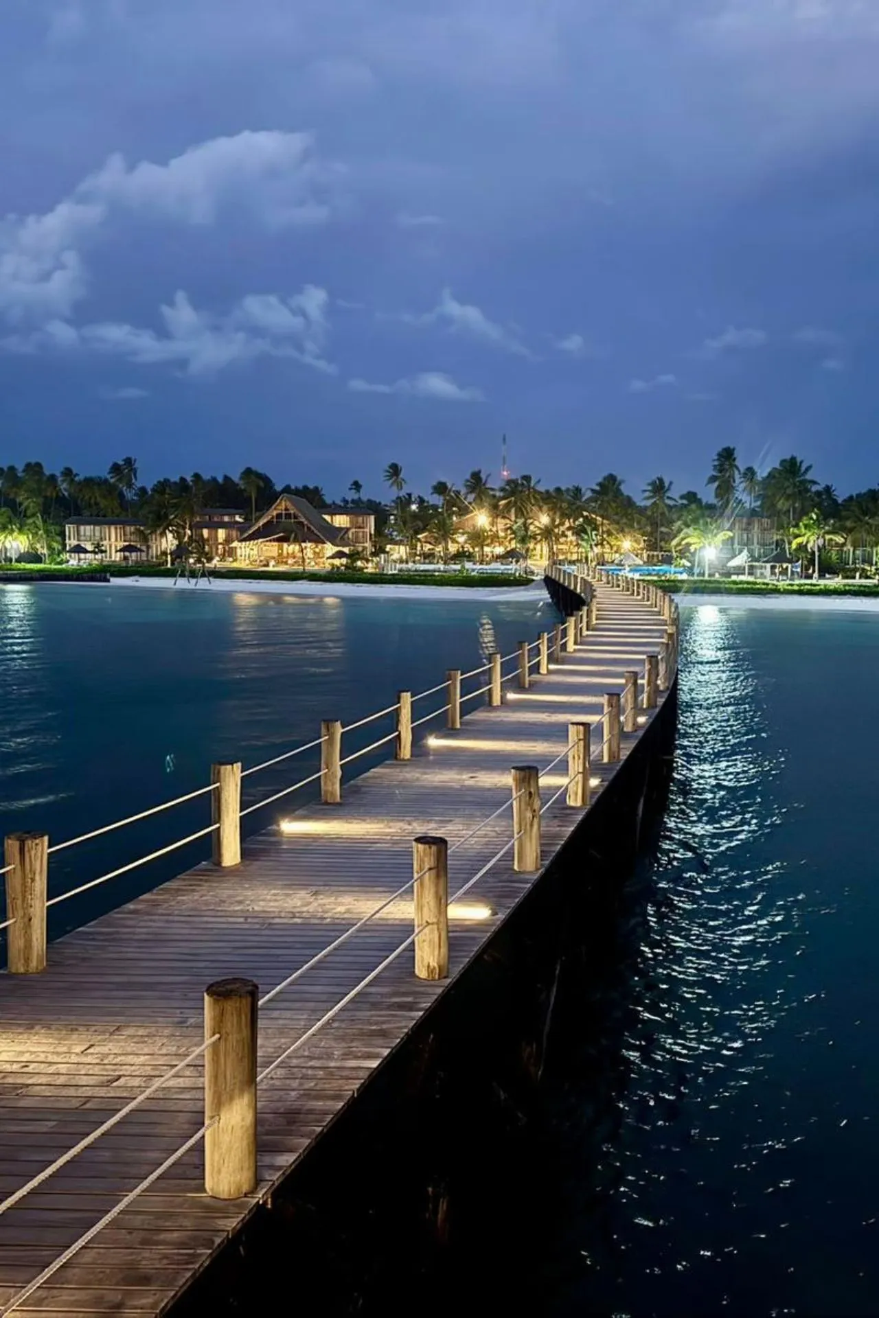Sfeervolle houten pier van het Jaz Elite Aurora Beach Resort op Zanzibar in de avonduren. De verlichte aanlegsteiger loopt de Indische Oceaan in en biedt een prachtig uitzicht op het resort. Deze iconische jetty is een populaire plek om te genieten van de zonsondergang tijdens een vakantie op Zanzibar.
