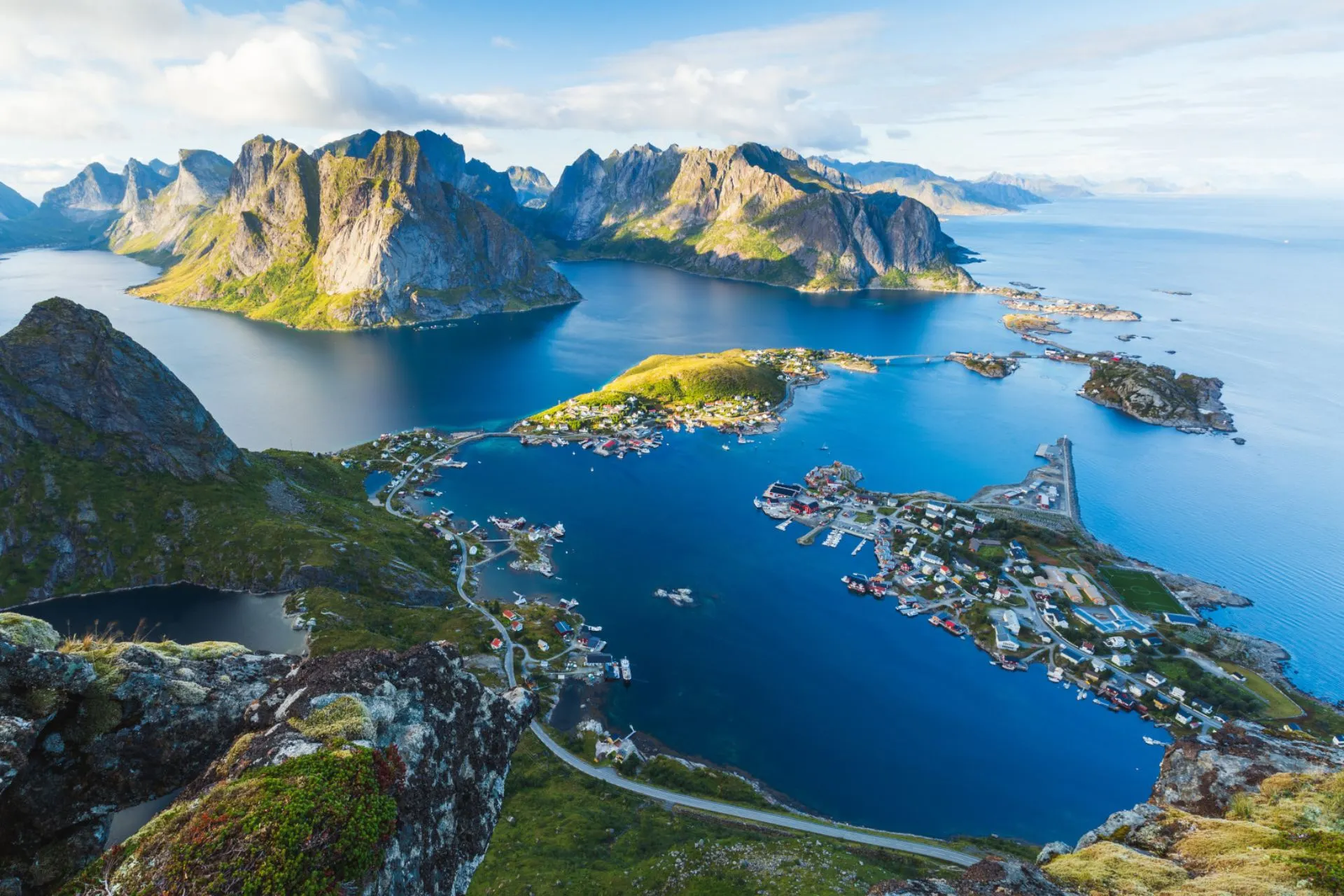 Luchtfoto van dramatisch fjordlandschap in Noorwegen met steile bergen, blauwe fjorden en verspreide dorpjes langs de kust.