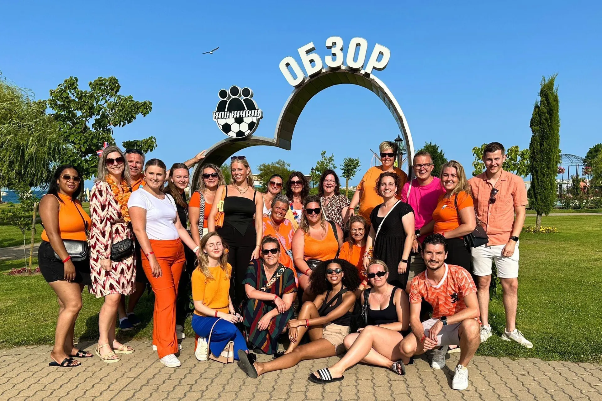 Lachende groep jongeren op de foto in Sunny Beach, Bulgarije, met zomerse sfeer op de achtergrond.