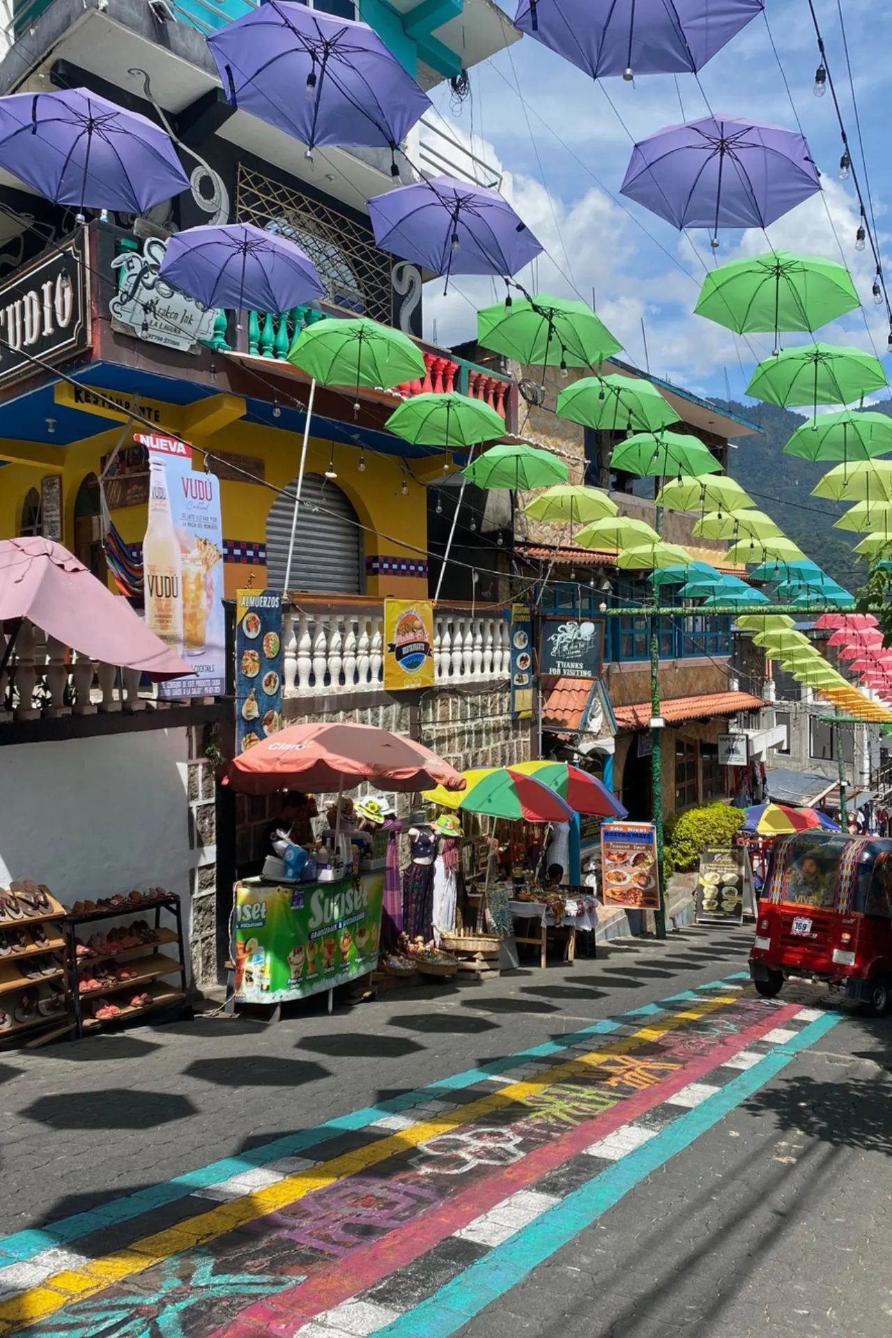 Kleurrijke straat in San Pedro La Laguna aan Lake Atitlán, met gekleurde paraplu’s boven de weg.
