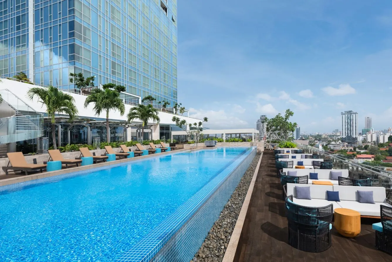 Infinity rooftop zwembad van Courtyard by Marriott Colombo met uitzicht op de skyline van de stad. Loungebedden en stijlvolle zithoeken met palmbomen en blauwe lucht zorgen voor een ontspannen sfeer.