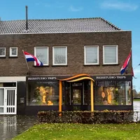 Filiaal Travelcenter de Wit in Asten, landelijk gebouw met een mooie blauwe lucht, de Nederlandse vlag hangt uit.