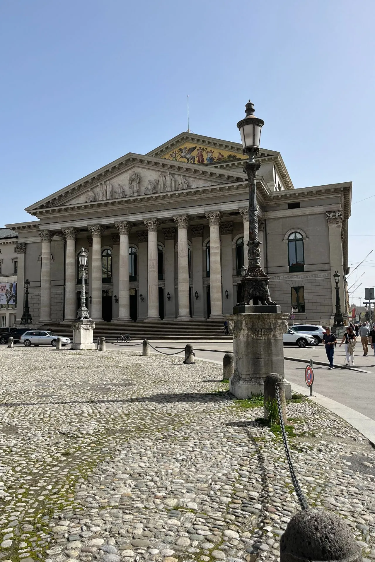 De imposante façade van de Bayerische Staatsoper in München, met majestueuze pilaren en een historische uitstraling op een zonnige dag.