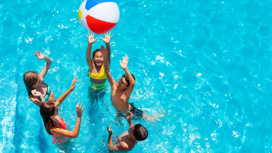 Kinderen op vakantie spelen in het zwembad met een bal