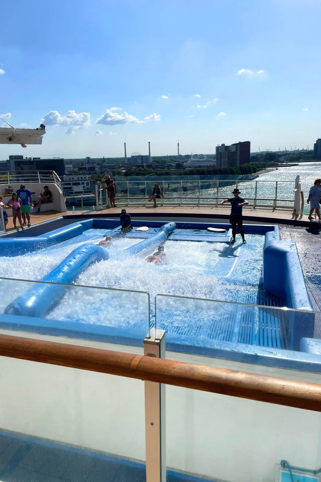 FlowRider surf simulator op het dek van de Independence of the Seas, waar gasten plezier hebben met bodyboarden en surfen met uitzicht over de stad en de rivier.