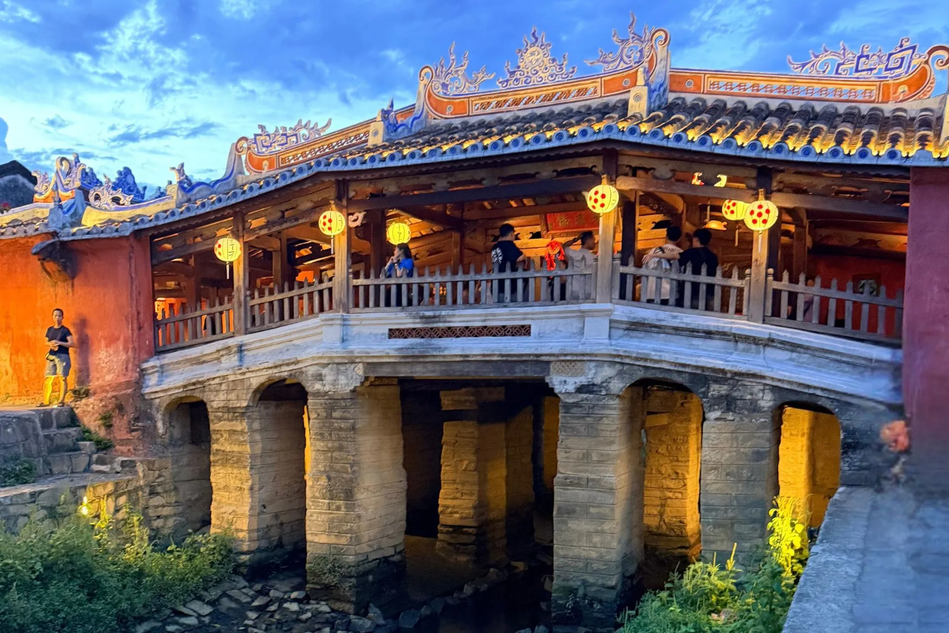 De iconische Japanse Overdekte Brug in Hoi An, Vietnam, verlicht tijdens de avonduren. Deze historische brug uit de 16e eeuw is een van de bekendste bezienswaardigheden van de UNESCO-stad Hoi An en weerspiegelt de rijke geschiedenis, cultuur en architectuur van centraal Vietnam.