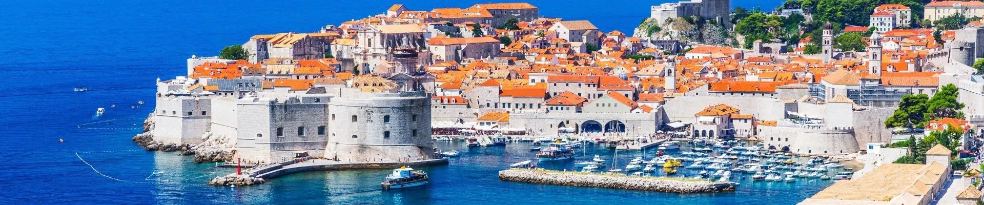 Panoramisch uitzicht op Dubrovnik in Kroatië, met de iconische stadsmuren, sfeervolle oude binnenstad, haven en het helderblauwe water van de Adriatische Zee.