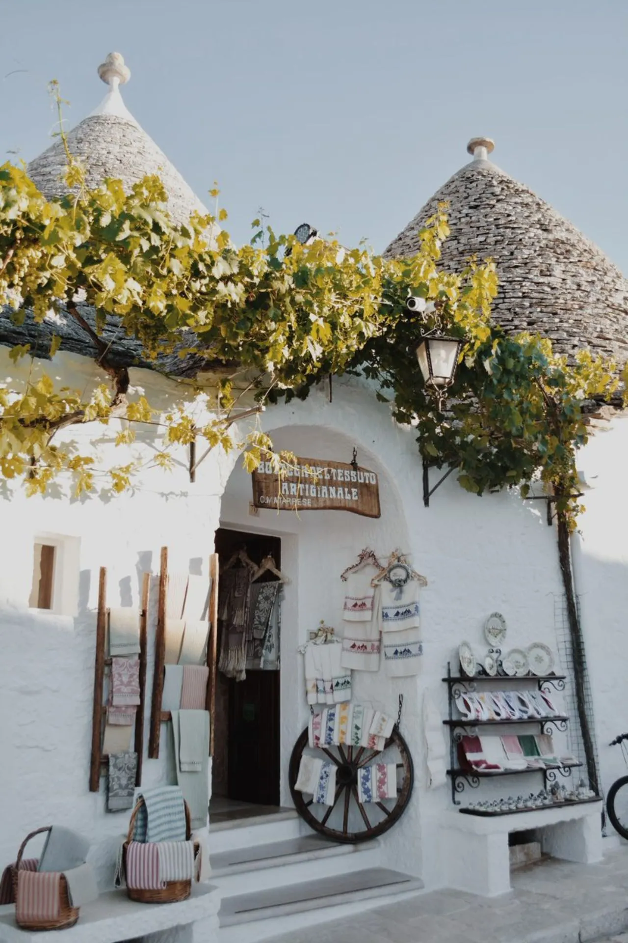 Een charmante trullo met groene bladeren en kleine prullaria in Alberobello, Puglia.