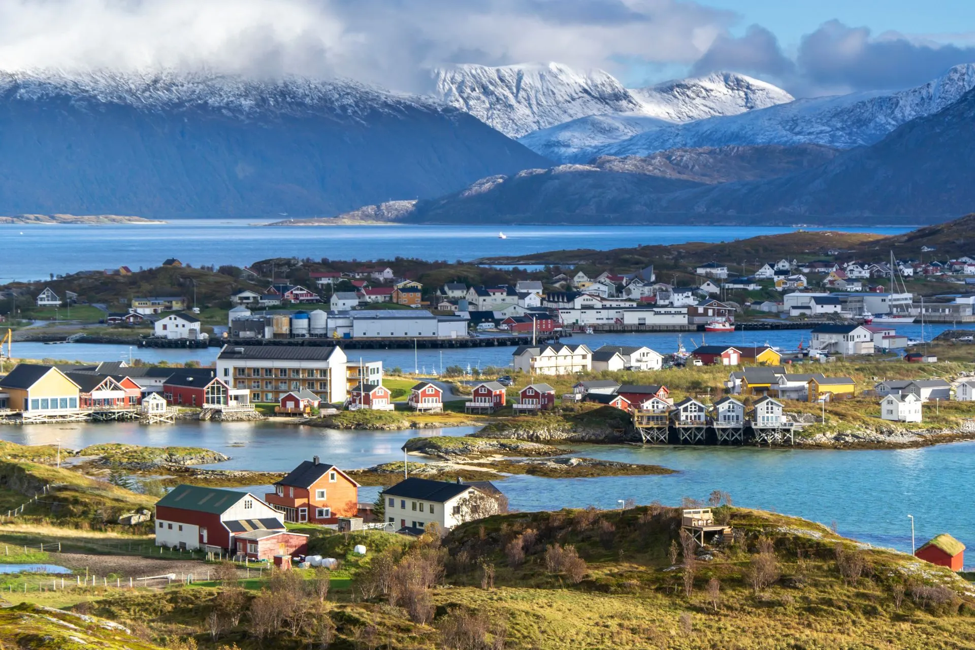 Uitzicht over het stadje Tromsø in Noord-Noorwegen met kleurrijke huisjes aan het water en met sneeuw bedekte bergen op de achtergrond.