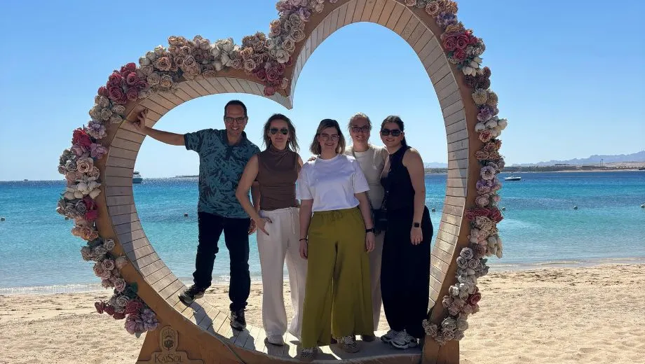 Groepsfoto tijdens een studiereis in Sahl Hasheesh, Egypte, met uitzicht op de Rode Zee en luxe resorts op de achtergrond.

