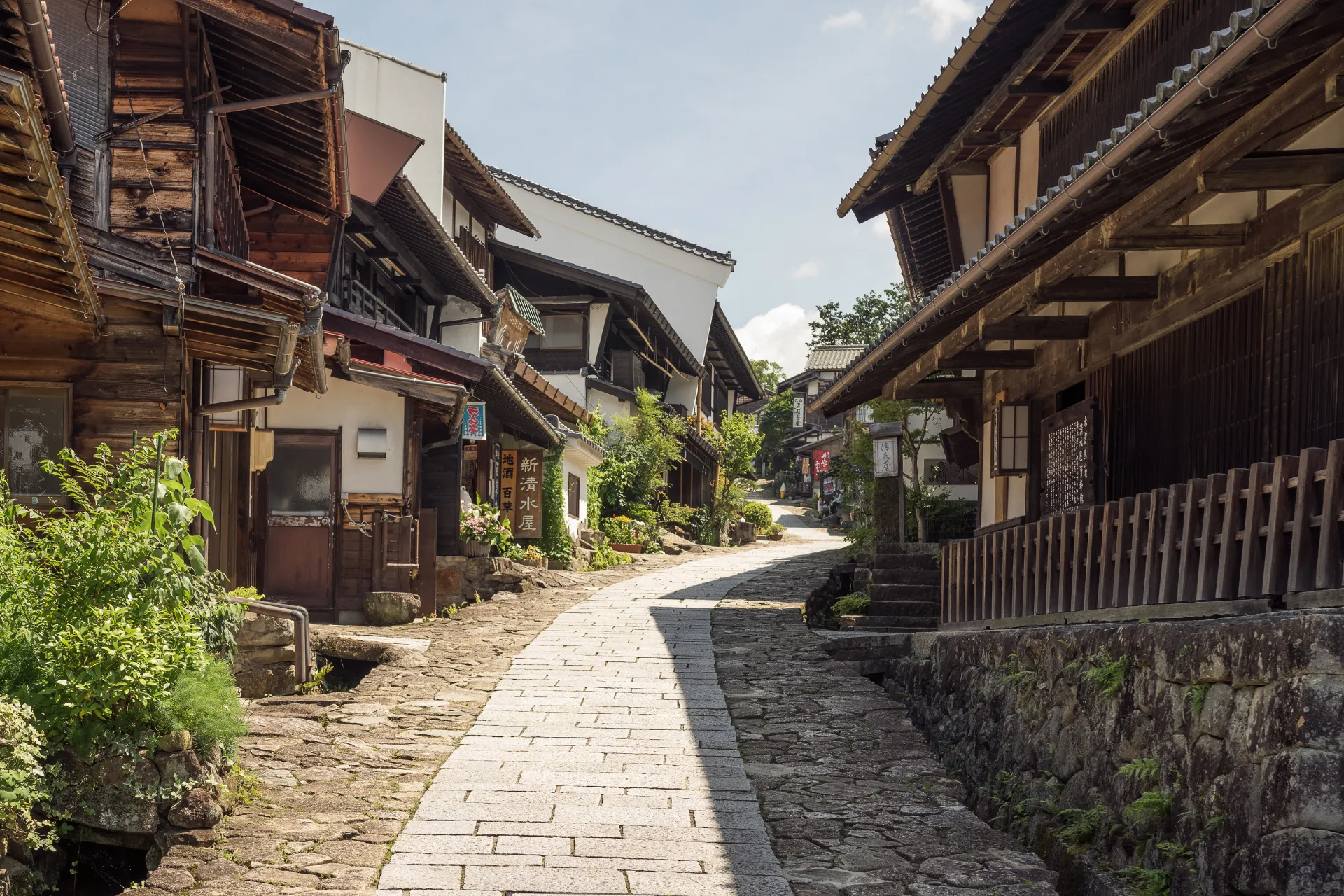Een charmant houten huisje langs de oude handelsroute van de Nakasendo, met een rustige straat omgeven door natuur, die het traditionele Japanse dorpsgevoel uitstraalt.