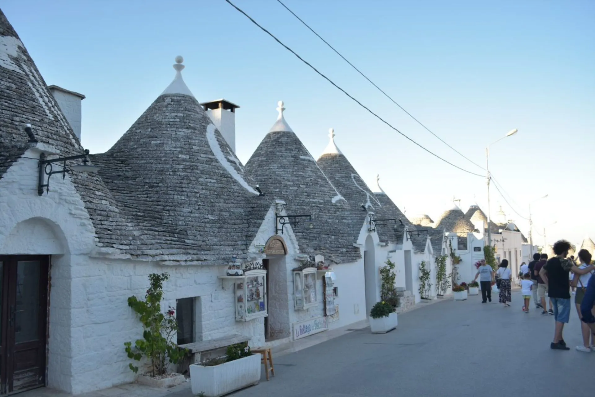 Rijtje iconische trulli-huizen in Puglia met kegelvormige daken en witte muren.