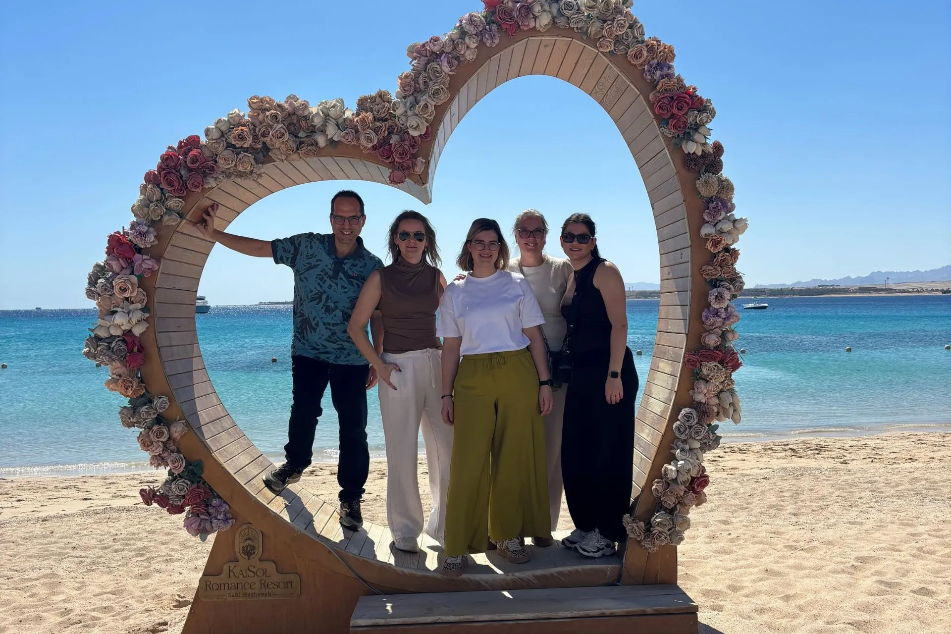 Groepsfoto tijdens een studiereis in Sahl Hasheesh, Egypte, met uitzicht op de Rode Zee en luxe resorts op de achtergrond.

