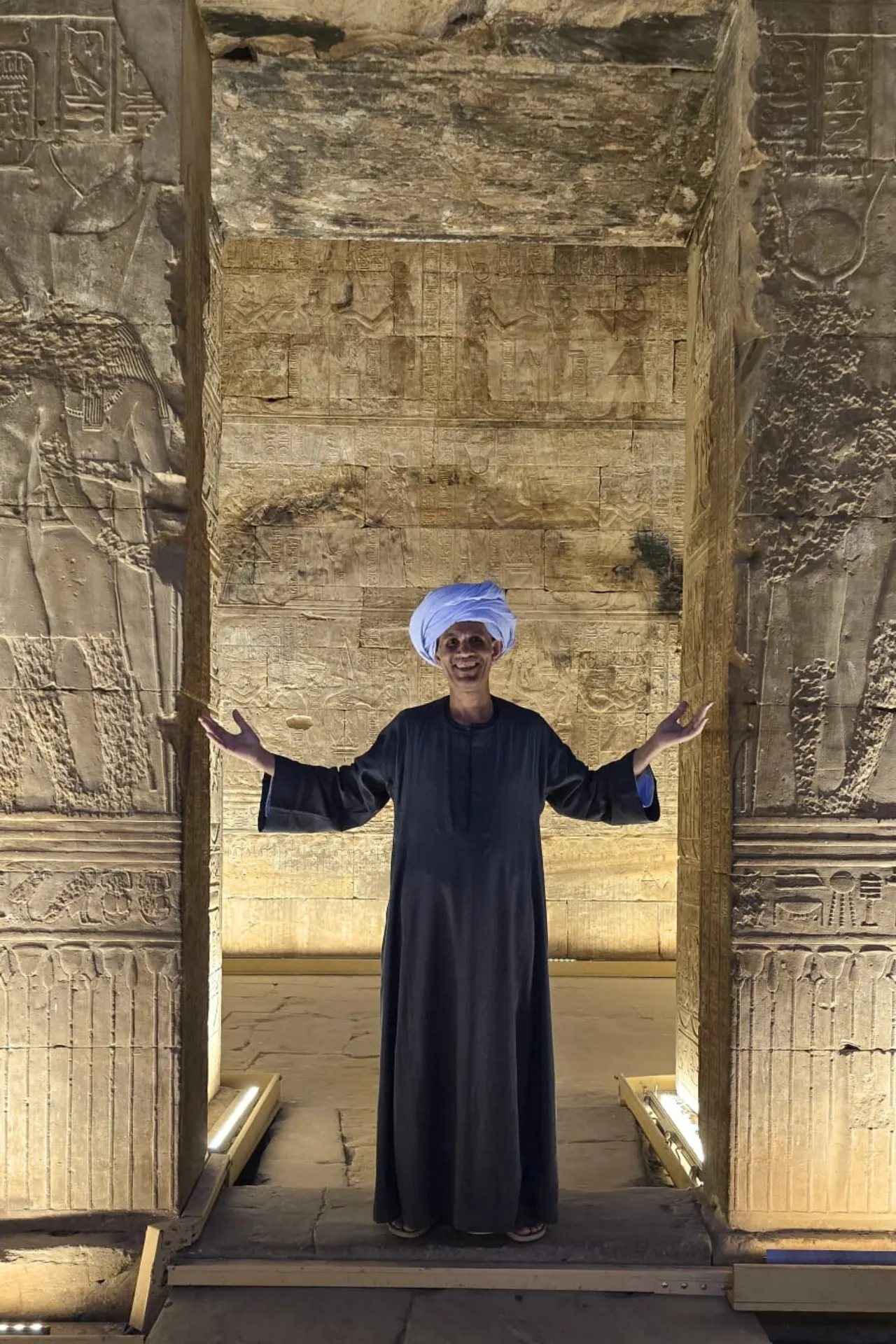 Egyptische man in traditionele lange jurk en tulband staand in een grote stenen opening in Luxor Egypte.