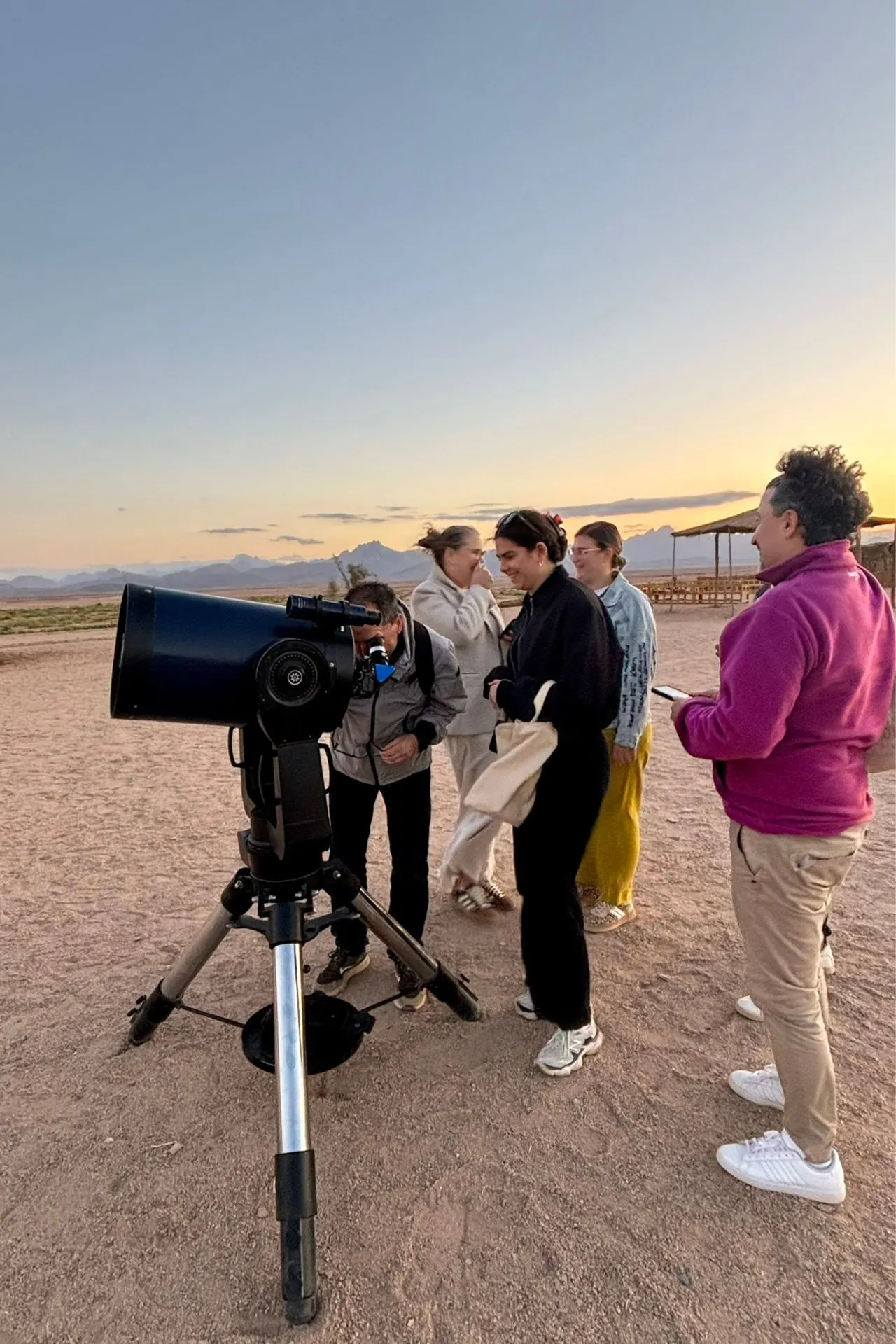 Groep reisagenten bekijkt de sterrenhemel met een telescoop in de Egyptische woestijn bij zonsondergang