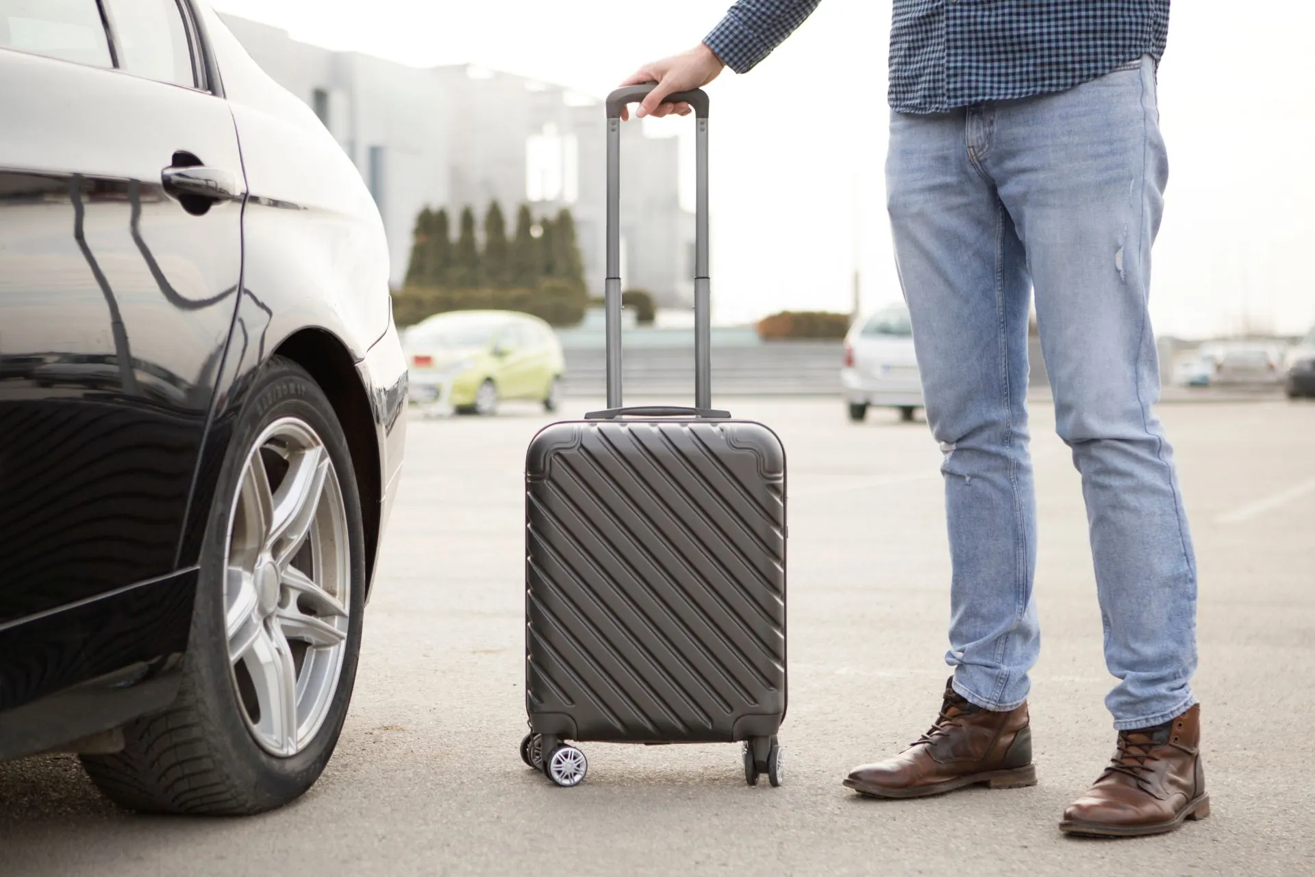 Man met koffer naast auto op parkeerplaats Weeze Airport – eenvoudig parkeren bij Weeze Airport voor goedkope vluchten en vertrek vanaf luchthaven Weeze.