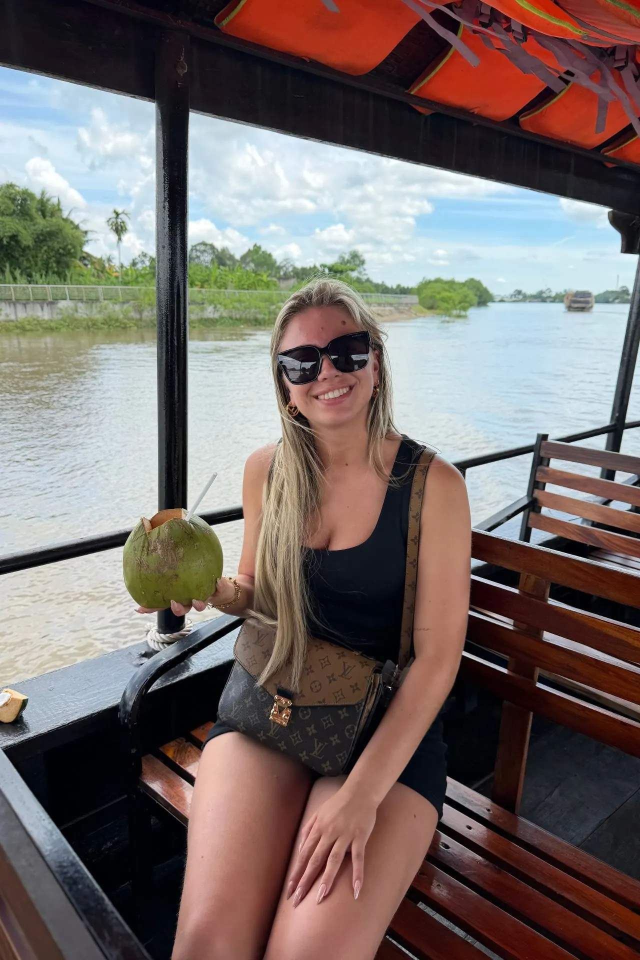 Boottocht over de Mekong-rivier in Vietnam, met uitzicht op het groene landschap en traditionele waterwegen. Een verse kokosnoot aan boord maakt de ervaring compleet. De Mekong Delta staat bekend om haar tropische natuur, lokale cultuur en ontspannen sfeer.