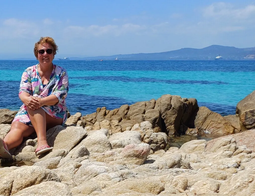 Dionne op het strand op Sardinië met rotsen en een blauwe zee.