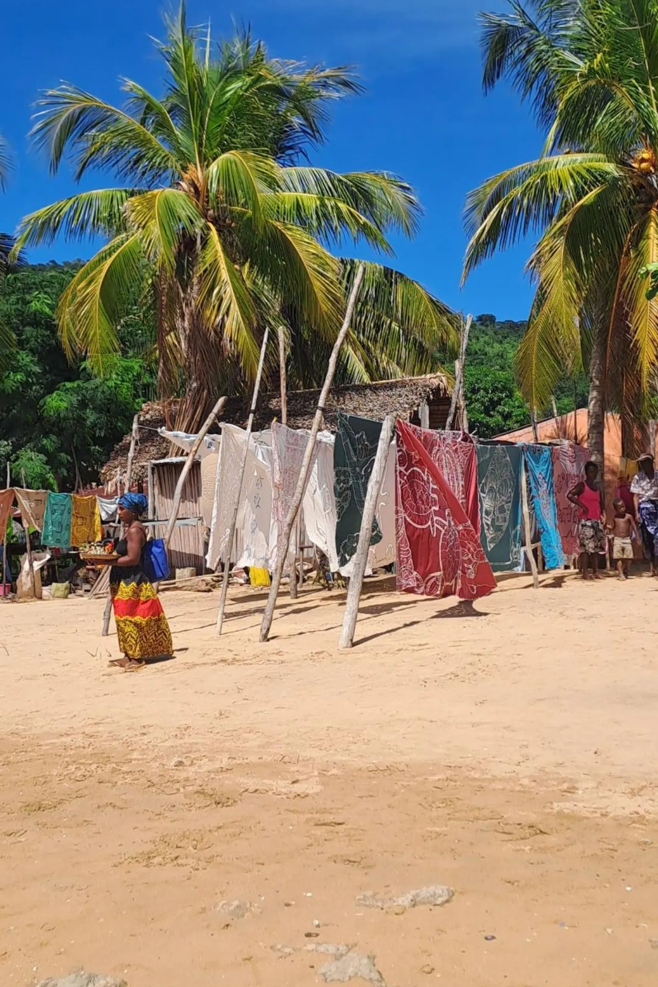 Gekleurde doeken hangen te drogen tussen palmbomen op het strand in Antsiranana, Madagaskar