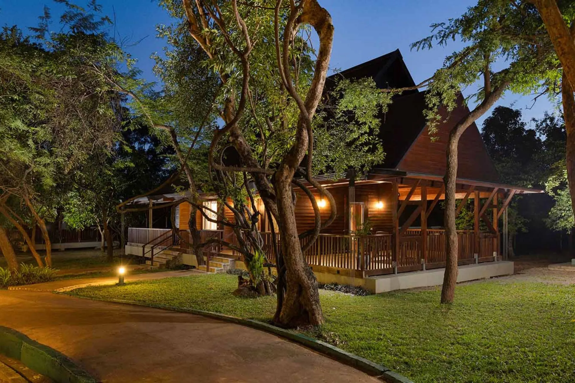  Sfeervol verlichte houten villa in een bosrijke omgeving bij Occidental Paradise Dambulla, gefotografeerd in de avond met omringende bomen en een rustig wandelpad.
