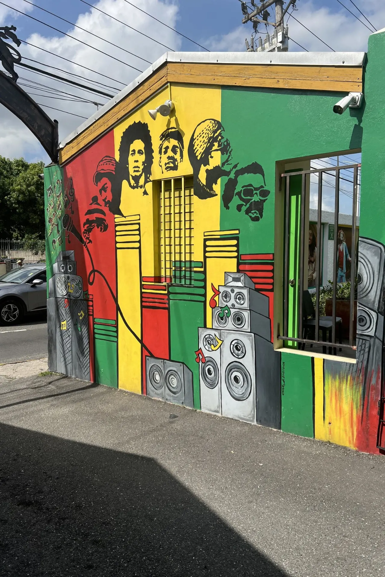 Vrolijke en opvallende muurschildering in groen, geel en zwart – de kleuren van Jamaica, vol karakter en energie.