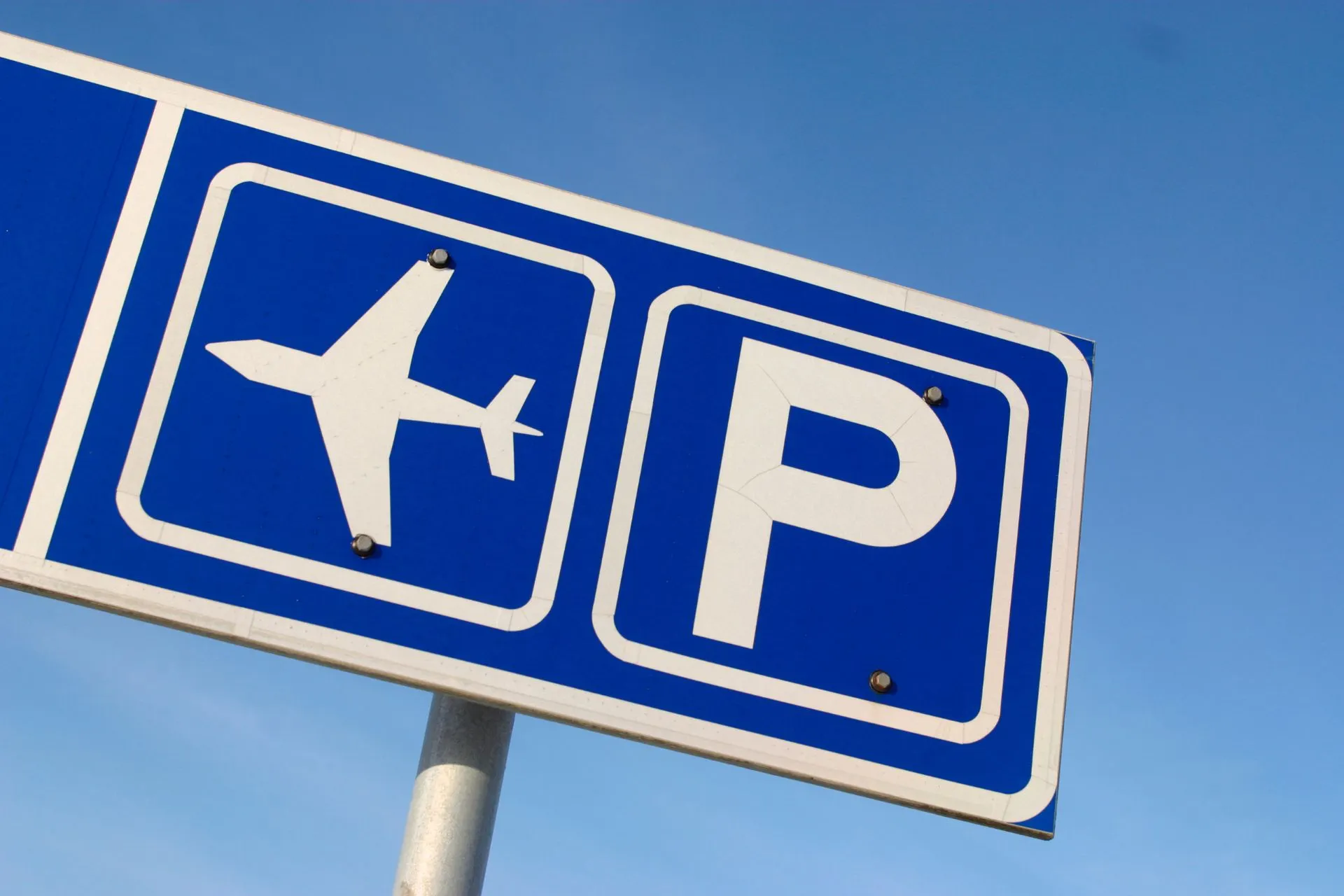 Blauw luchthavensymbool met parkeeraanduiding, handig voor goedkope vluchten met eigen vervoer.