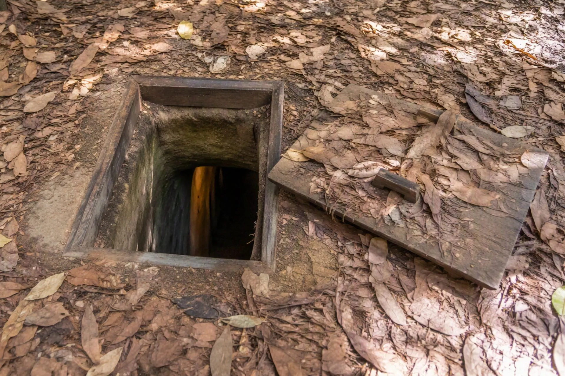 Verborgen toegang tot de beroemde Củ Chi Tunnels bij Ho Chi Minhstad, Vietnam. Dit smalle tunnelstelsel werd tijdens de Vietnamoorlog gebruikt als schuilplaats, verbindingsroute en strategische uitvalsbasis. Een indrukwekkende historische bezienswaardigheid die inzicht geeft in het verleden van Vietnam.