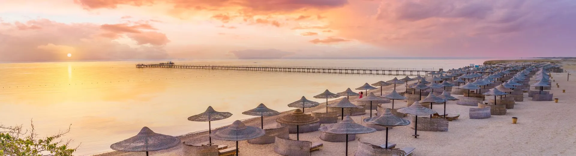 Zonsondergang bij het strand van Hurghada  in Egypte met ligbedden en parasols bij luxe resorts aan de Rode Zee
