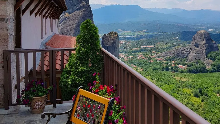 "Charmant terras van een Meteora-klooster in Griekenland, met houten balustrade, kleurrijke bloemen en een adembenemend uitzicht op rotsformaties en groene valleien. Deze plek biedt rust en spiritualiteit in een unieke natuurlijke omgeving. Ideaal voor reizigers die cultuur, natuur en fotografie willen combineren. Ontdek Meteora’s kloosters, wandelpaden en indrukwekkende landschappen in Centraal-Griekenland."