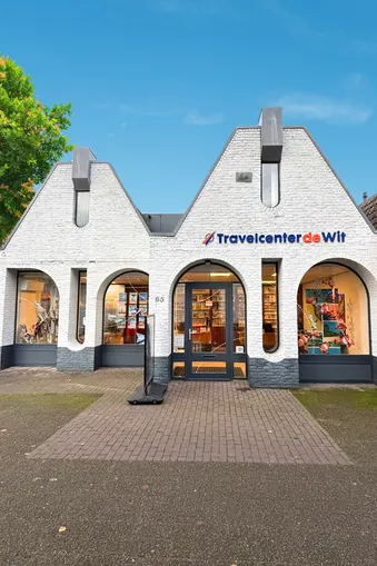 Vestiging Travelcenter de Wit in Gemert, mooie blauwe lucht en groene boom.