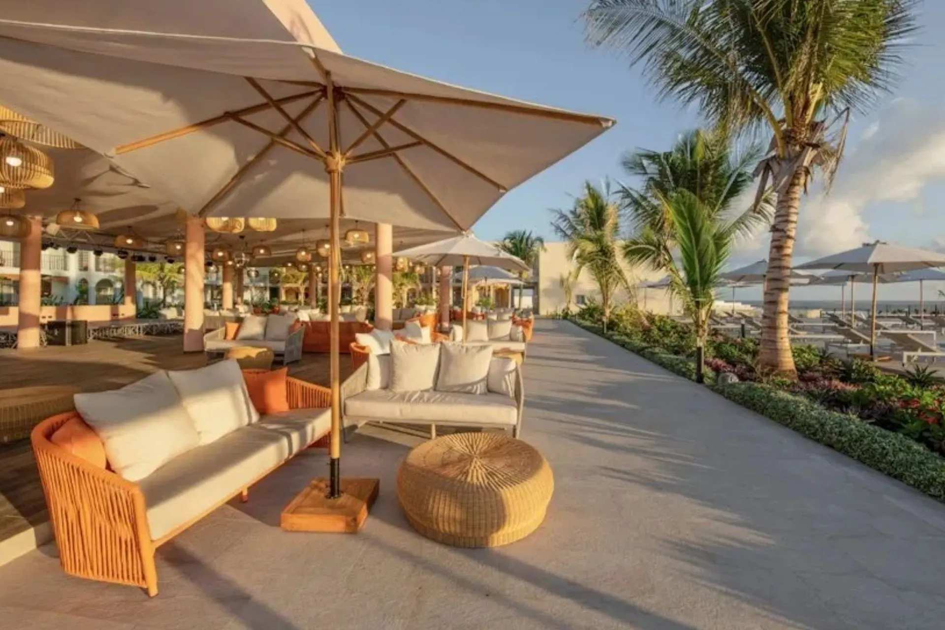 Stijlvolle buitenlounge van The Mora Zanzibar met comfortabele zitplaatsen, tropische palmbomen en uitzicht op het strand en de Indische Oceaan. Het luxe resort biedt moderne faciliteiten, een ontspannen sfeer en diverse plekken om te genieten van zon, zee en comfort op Zanzibar.