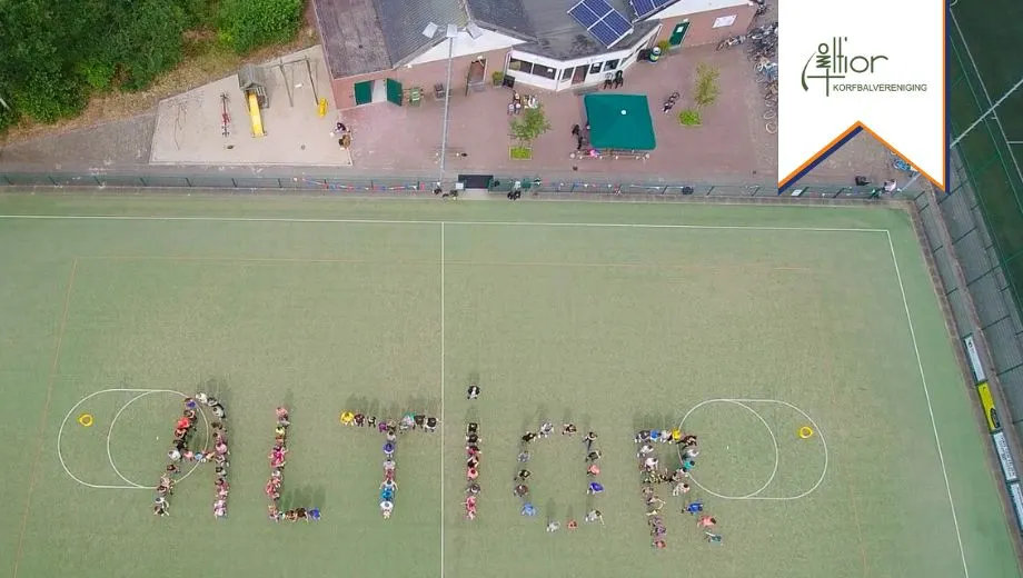 Een luchtfoto van het korfbalveld bij korfbalvereniging Altior, waarbij het woord 'Altior' is gevormd door mensen op het veld.