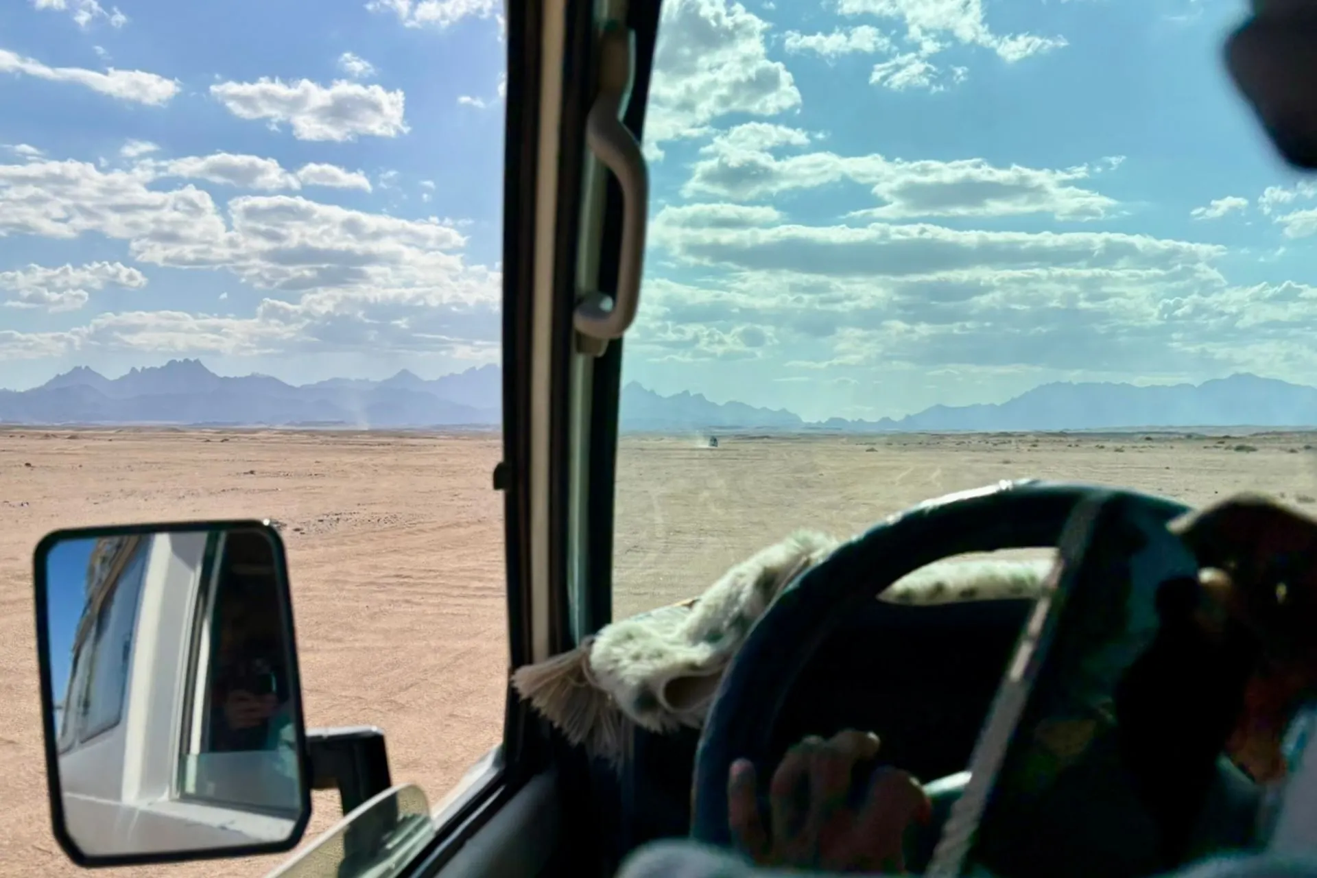 Uitzicht vanuit een jeep over de Egyptische woestijn met bergen aan de horizon tijdens een jeepsafari.