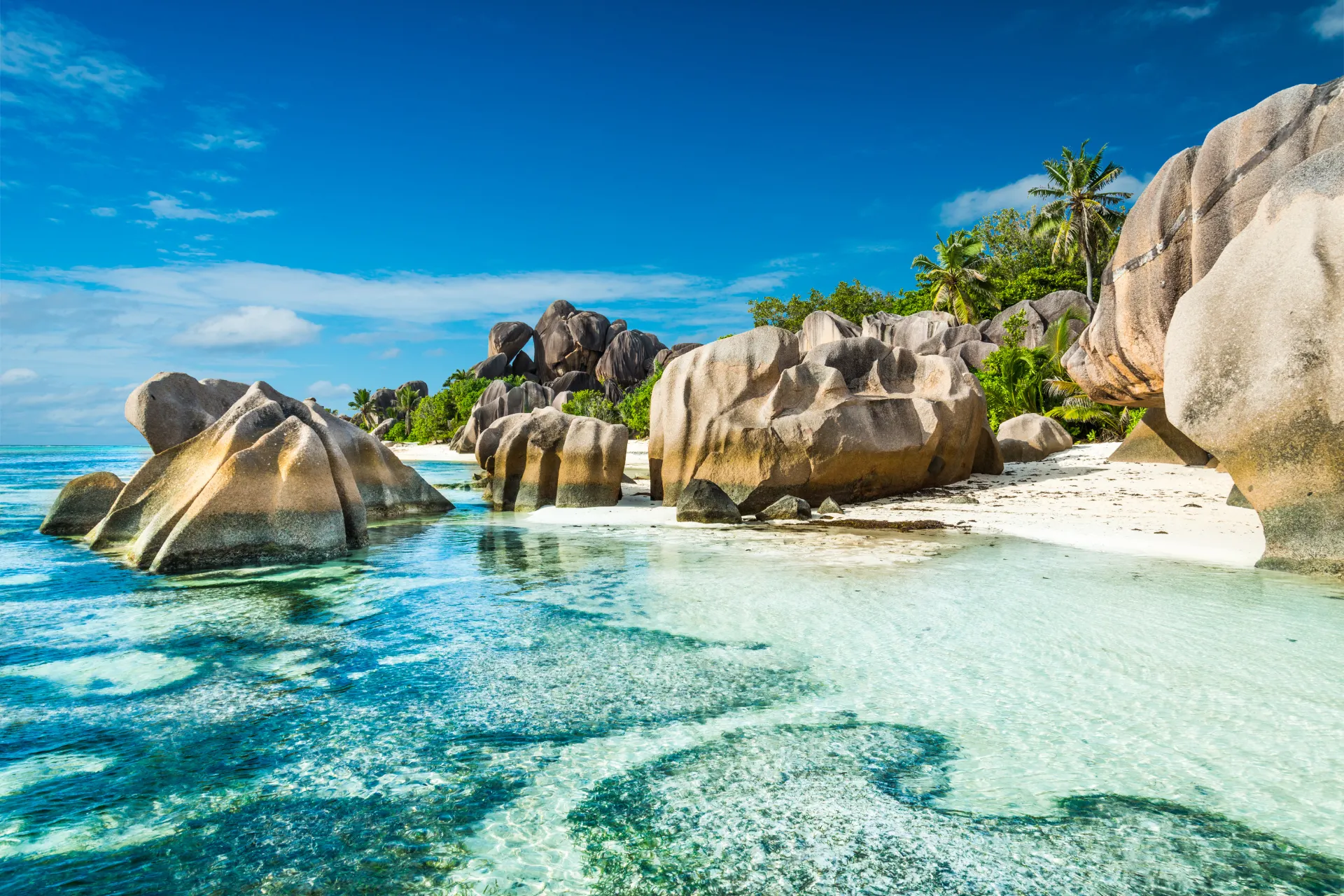 Helder blauw water met grote rotsblokken langs de kust van de Seychellen