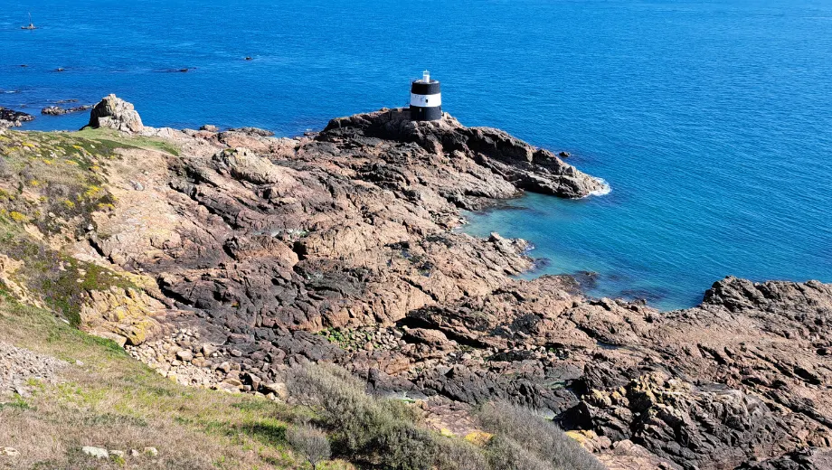 Rotsachtige kustlijn met een kleine zwart-witte vuurtoren op een uitstekende klif, omringd door helderblauw zeewater. De ruige rotsformaties en het diepe oceaanzicht creëren een indrukwekkend en natuurlijk landschap, ideaal voor kustwandelingen, fotografie en het ontdekken van maritieme bezienswaardigheden. Deze locatie biedt een panoramisch uitzicht over zee en is perfect voor toeristen die op zoek zijn naar rust, natuur en authentieke kustervaringen.