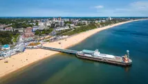 Kustlijn van Bournemouth in Zuid-Engeland met zandstrand, pier en zee onder een heldere lucht.