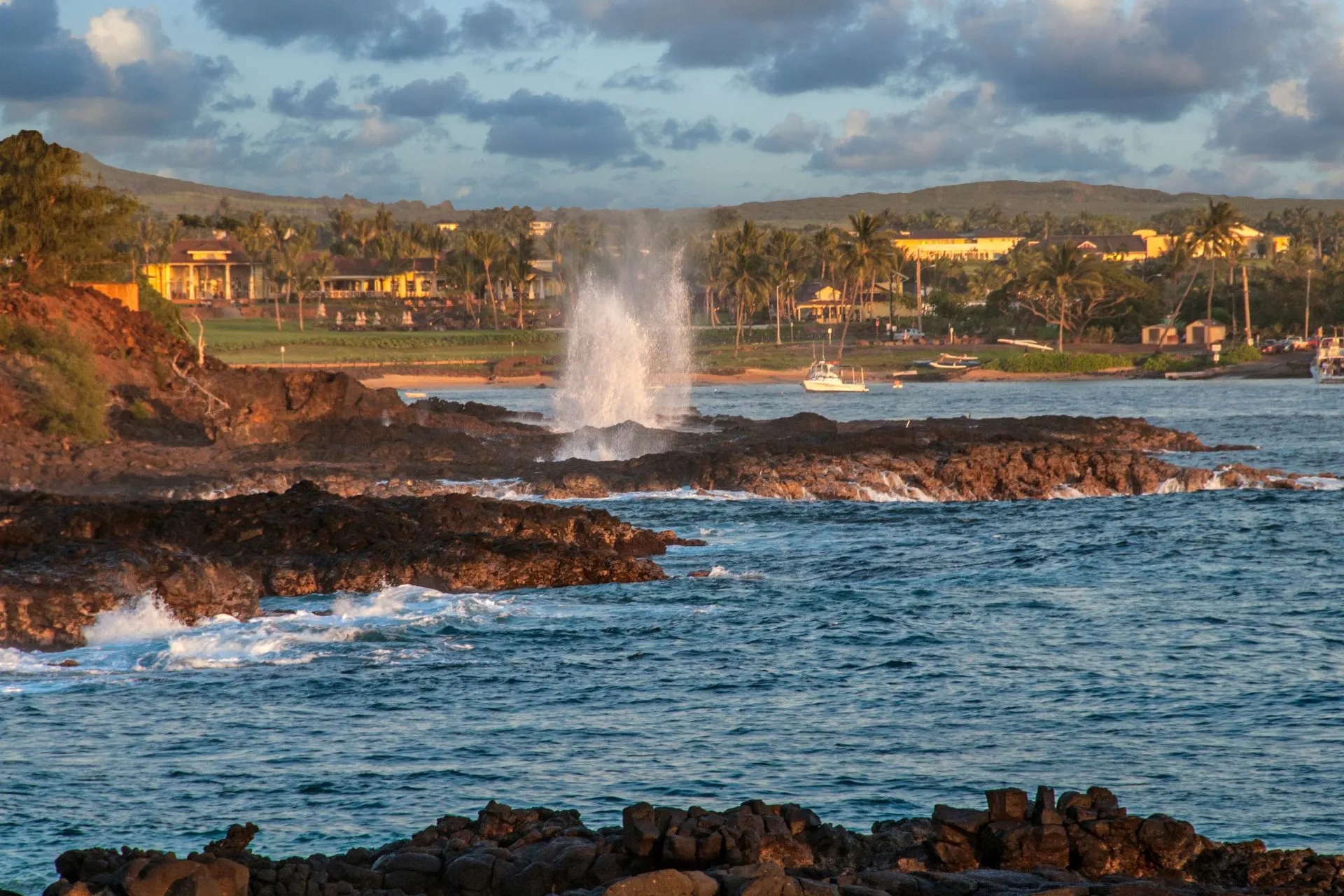 De Spouting Horn in actie op Kauai, met water dat krachtig omhoog spuit tegen een rotsachtige kustlijn.
