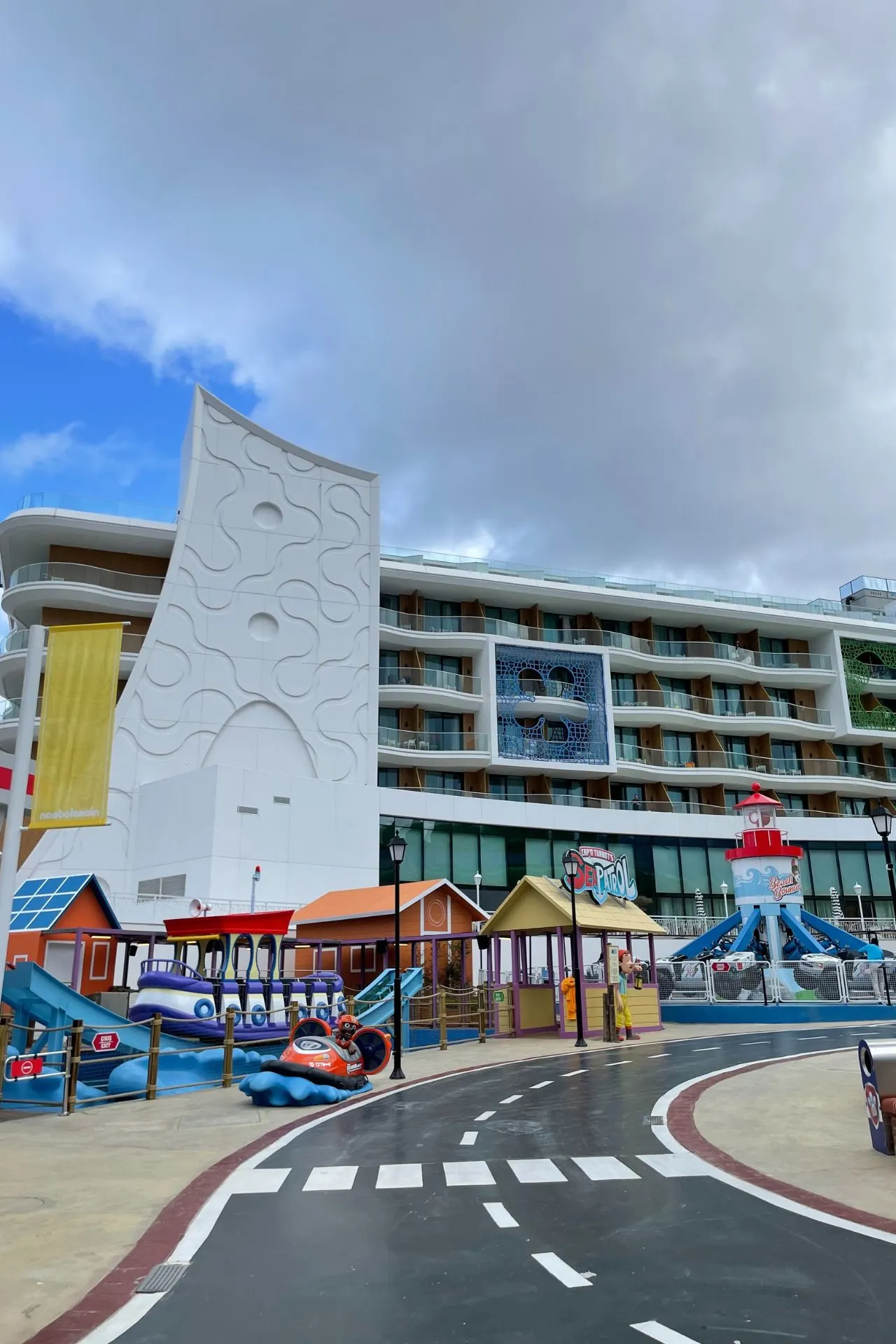 Buitenaanzicht van het Nickelodeon-hotel met een speeltuin, glijbanen en kleurrijke huisjes voor kinderen.