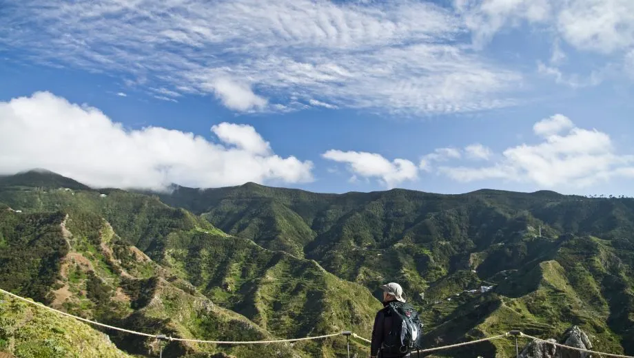 Uitzicht over een groen berglandschap vanaf een wandelpad in het noorden van Tenerife, met wolkenluchten boven de heuvels.