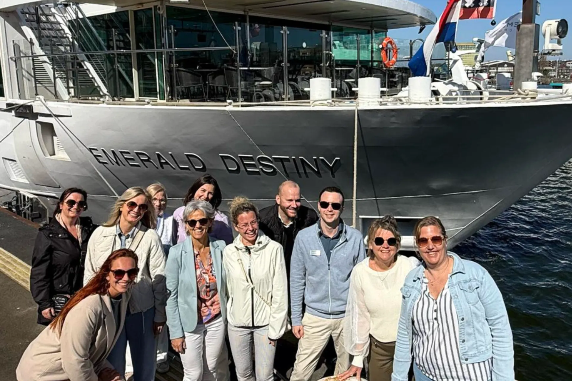 Groepsfoto van deelnemers aan de Emerald Cruise, poserend voor de Emerald Destiny aan de kade.