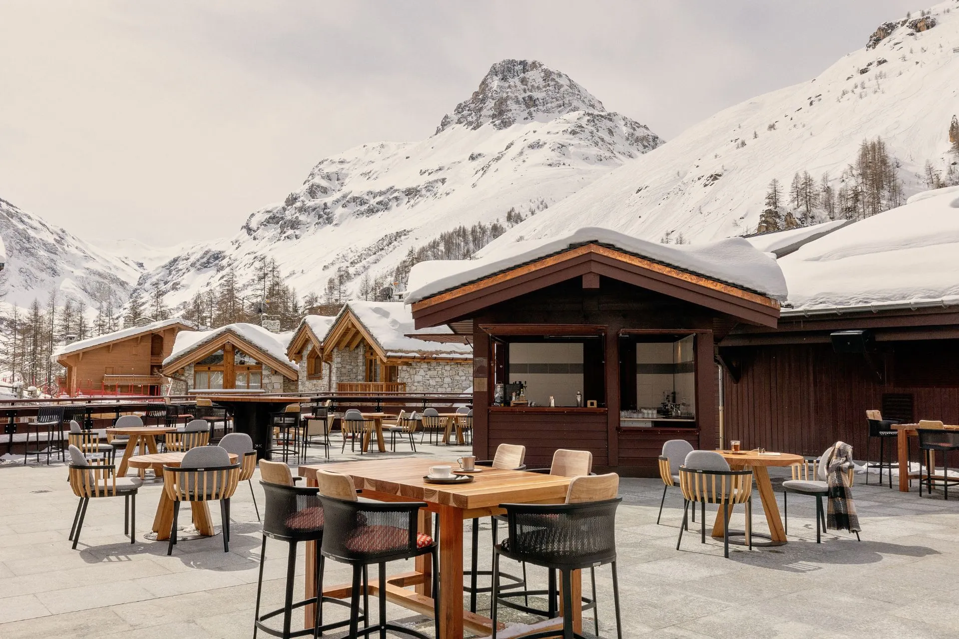 Club Med wintersportresort in de Franse Alpen met zonnig terras, houten chalets en uitzicht op besneeuwde bergtoppen. Geniet van all-inclusive skivakanties met gastronomische maaltijden, après-ski en luxe faciliteiten.