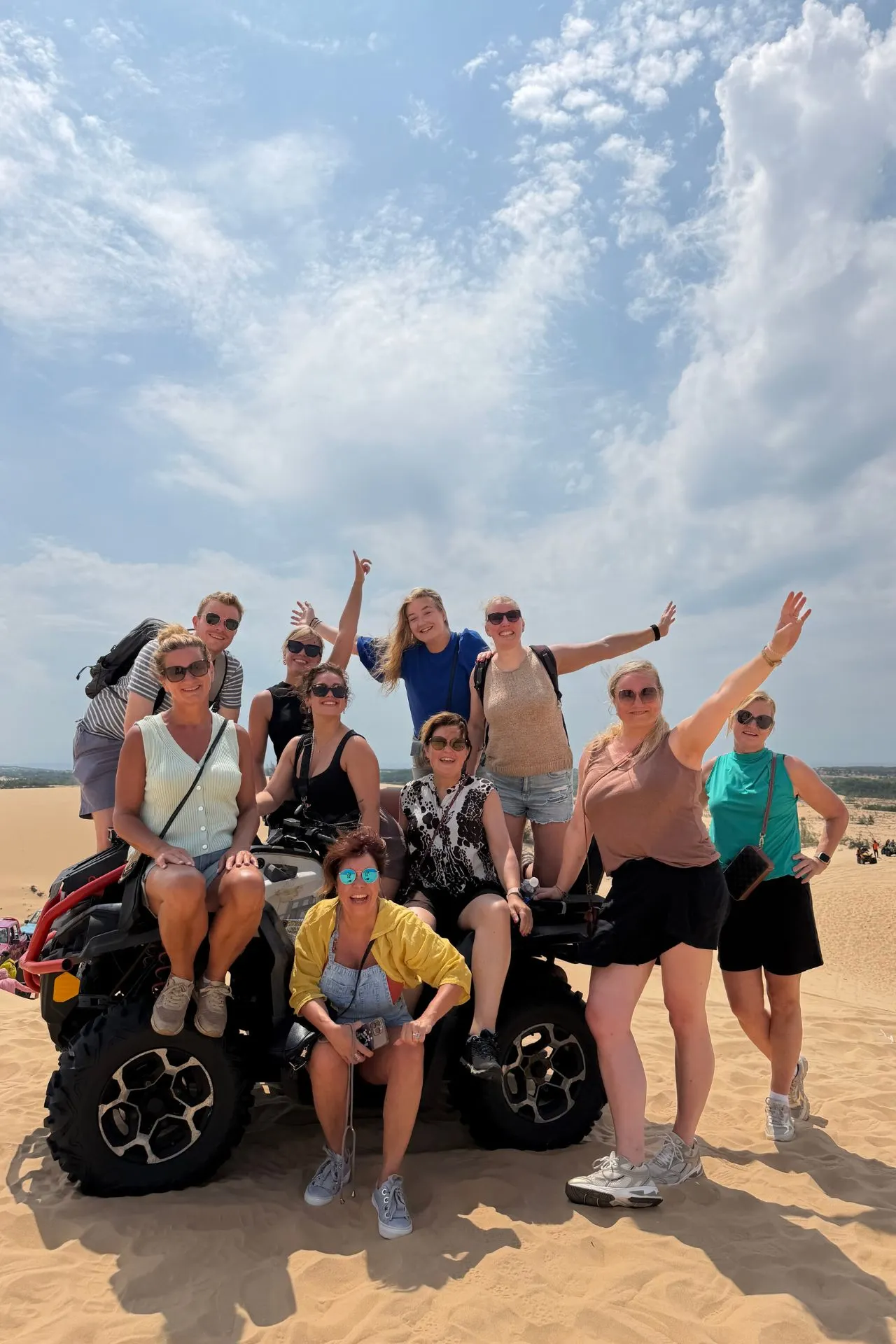 Reizigers poseren bij een quad in de uitgestrekte zandduinen van Mui Ne, Vietnam. De combinatie van gouden zandvlaktes, blauwe lucht en avontuurlijke excursies maakt deze locatie tot een van de meest bezochte hoogtepunten van Zuid-Vietnam.