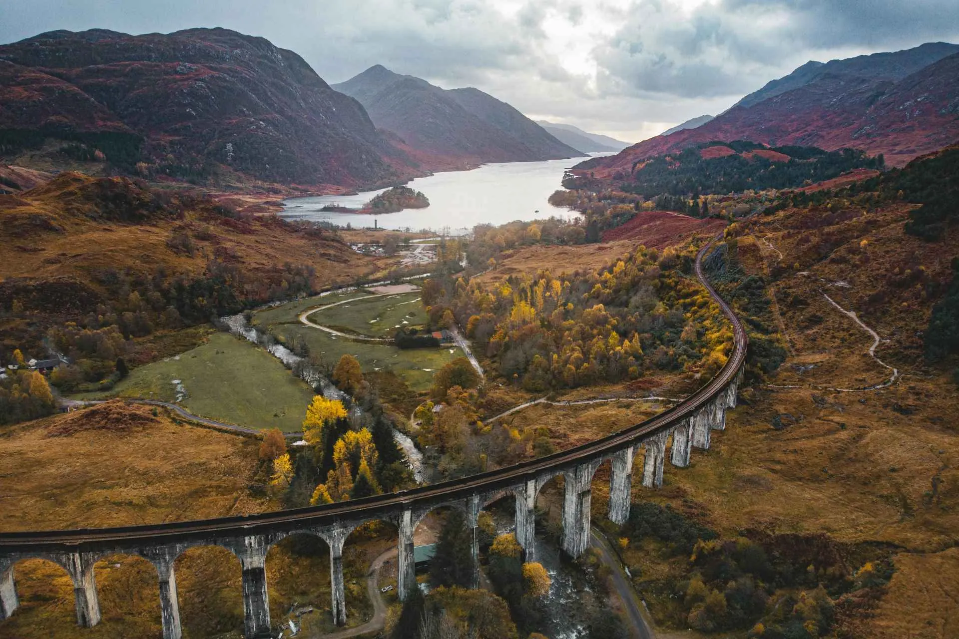 Jacobite Steam Train rijdt over het Glenfinnan Viaduct in de Schotse Hooglanden met uitzicht op bergen en een meer.
Het beroemde Glenfinnan Viaduct slingert door het indrukwekkende landschap van de Schotse Hooglanden
Glenfinnan Viaduct in de Schotse Hooglanden
