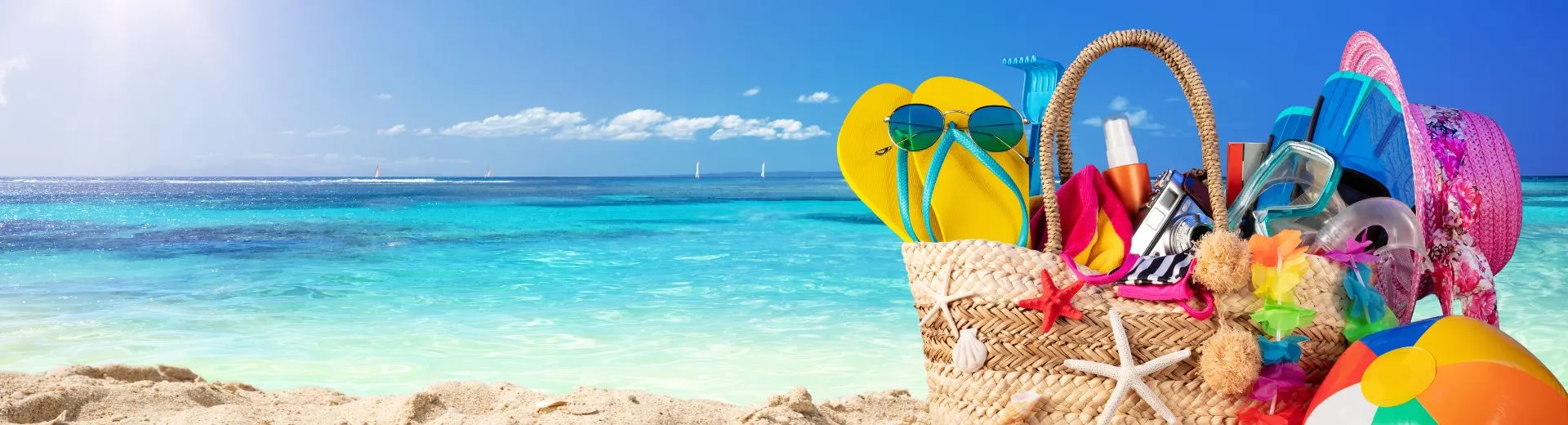 Strandtas met zomerse accessoires op het strand – ideaal voor een goedkope zomervakantie in 2026 dankzij vroegboekvoordeel.