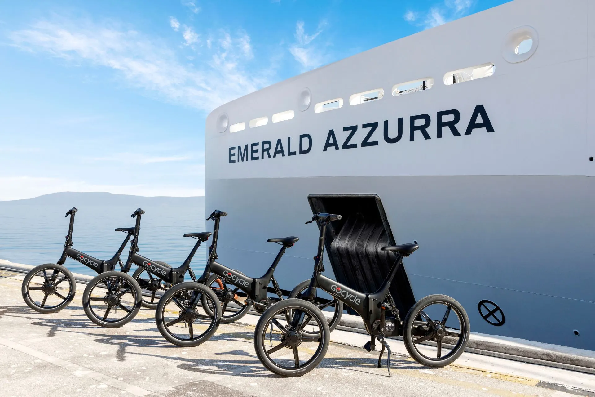 Een moderne vloot e‑bikes staat klaar op de kade naast het elegante jacht Emerald Azzurra, perfect voor actieve excursies tijdens een luxe cruise vakantie. Het strakke schip weerspiegelt in het kalme water terwijl de heldere lucht en rustige zee een ontspannen sfeer creëren. Deze combinatie van comfort, avontuur en verfijning benadrukt de unieke ervaring van een luxe zeecruise die zowel ontspanning als ontdekking biedt.