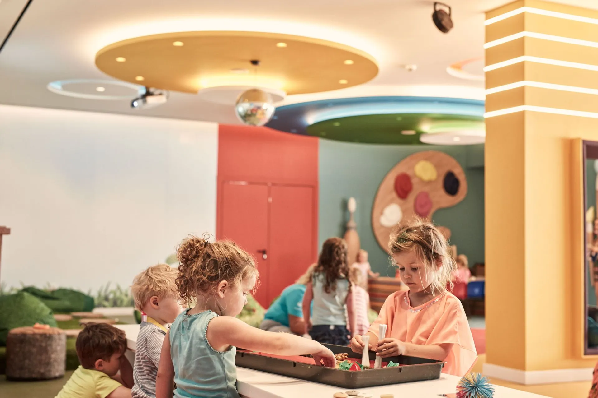 Kinderen spelen creatief in een kleurrijke en kindvriendelijke kidsclub van een Atlantica hotel. Ze knutselen aan tafels in een veilige, speelse omgeving met educatieve elementen, perfect voor gezinnen met jonge kinderen.