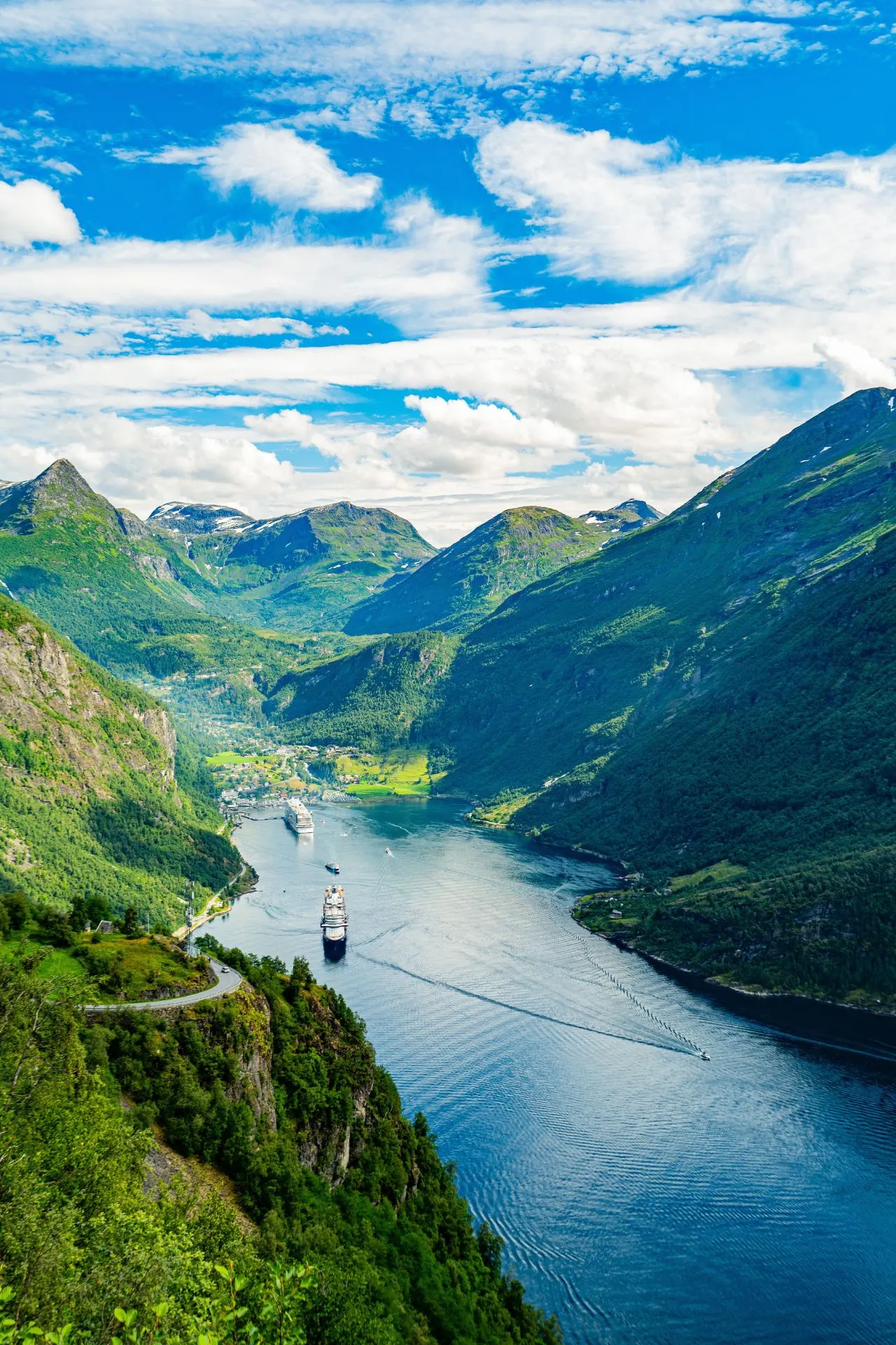 Cruiseschepen varen door een spectaculair Noors fjord, omringd door groene bergen en een helderblauwe lucht.